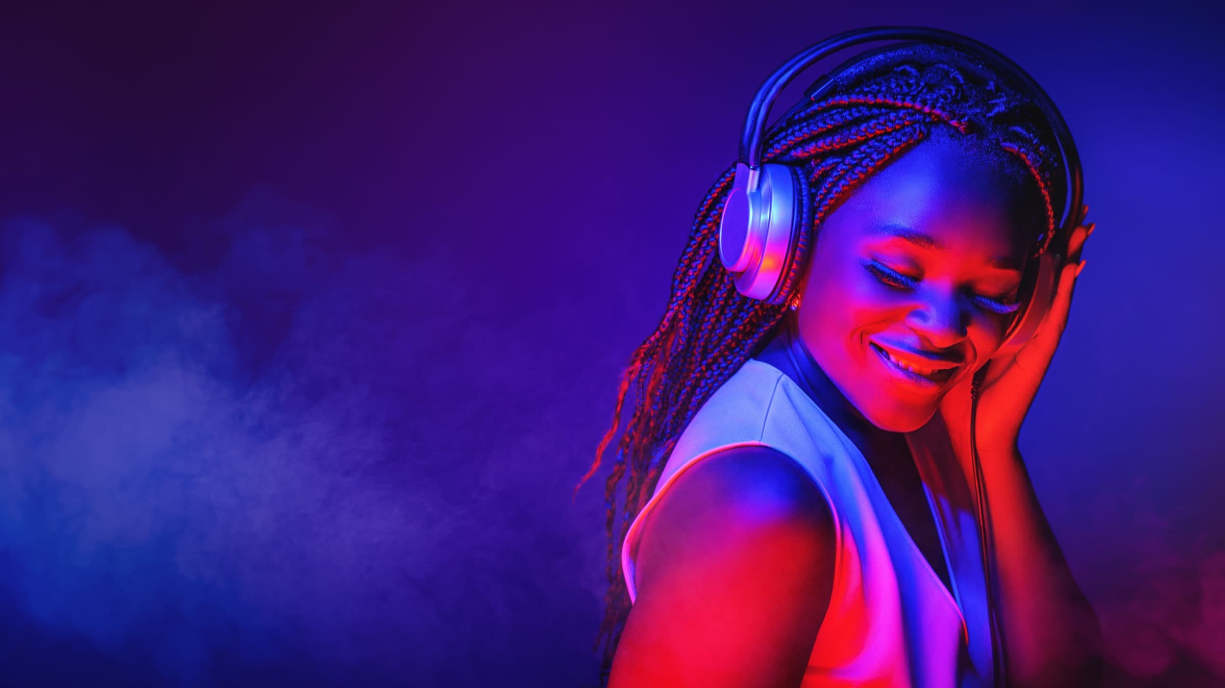 A woman lost in music, lit in neon pink and violet